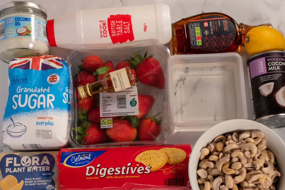 The ingredients that you need for my vegan strawberry cheesecake bars laid out over a white marble background. 