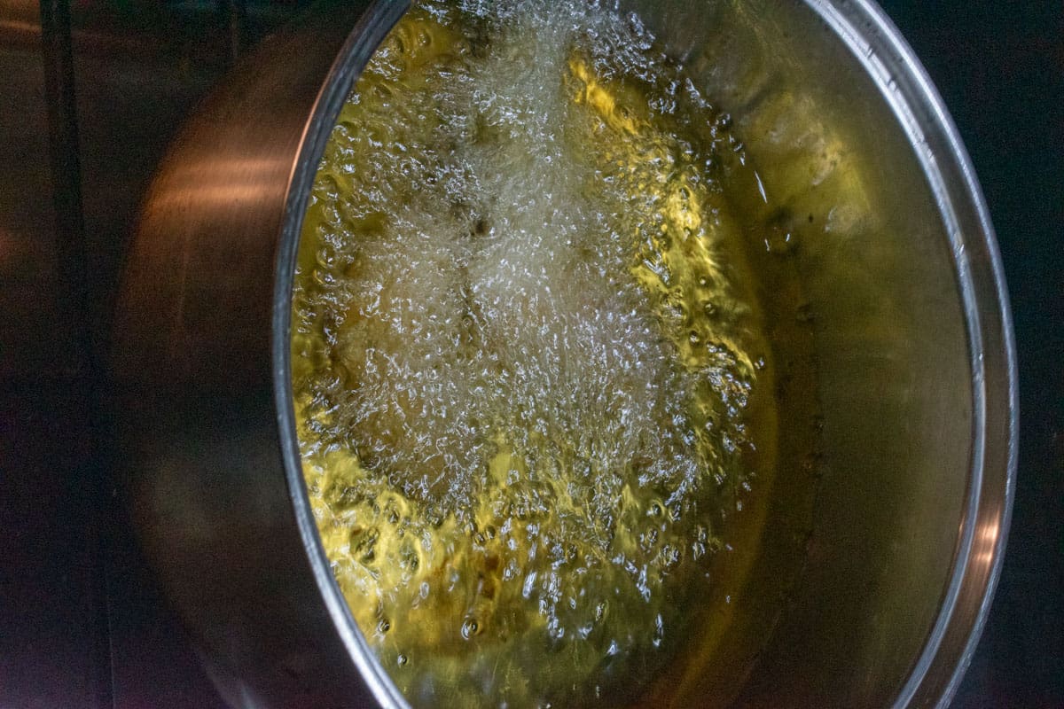 Oil boiling inside a large, metal pot. 