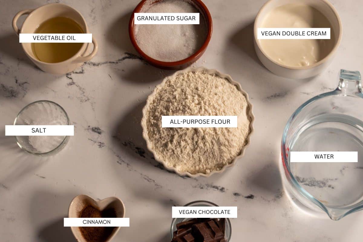 The ingredients needed to make vegan churros laid out neatly on a white, marble background. 