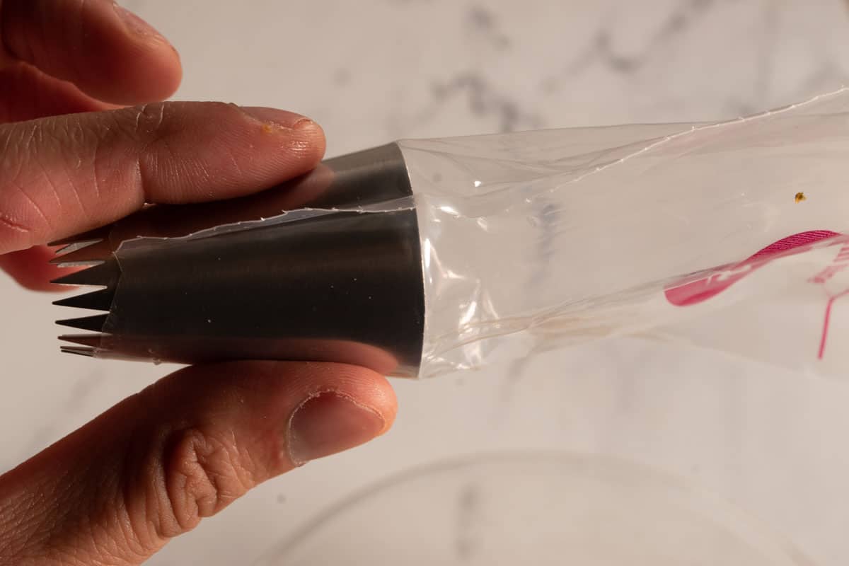 A disposable piping bag with a large star attachment fitted.