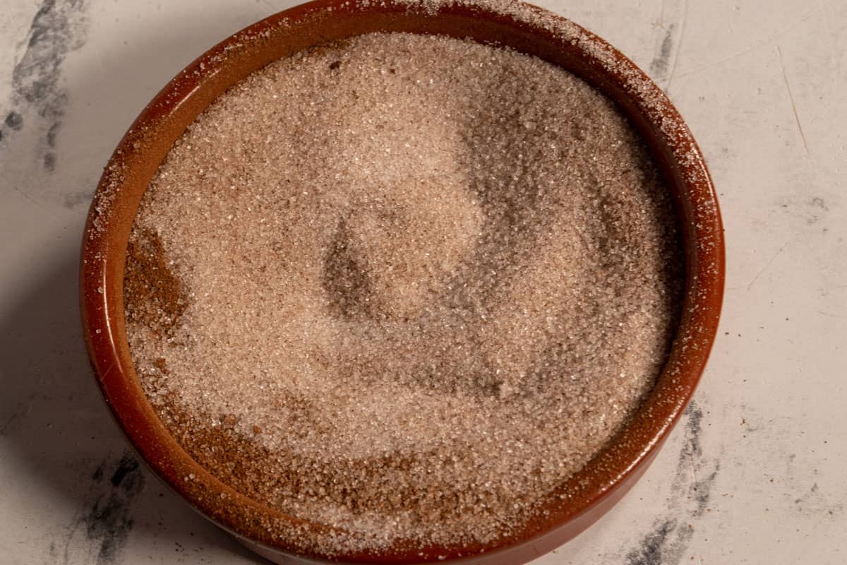 The cinnamon sugar mixed together inside a large, brown ramekin. 