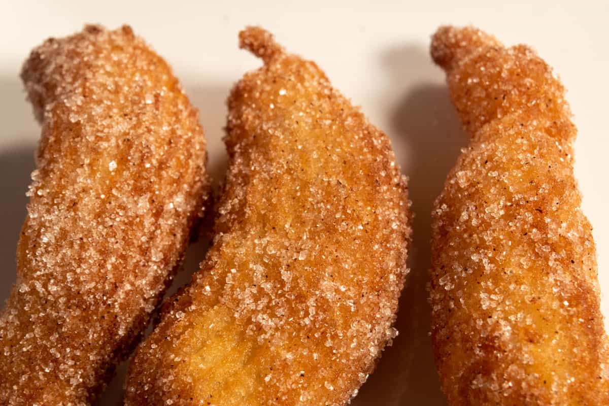 Fried, golden brown vegan churros coated in cinnamon sugar and cooling. 