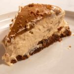 A large, chunky slice of vegan Biscoff cheesecake on a white plate.
