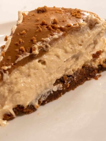 A large, chunky slice of vegan Biscoff cheesecake on a white plate.