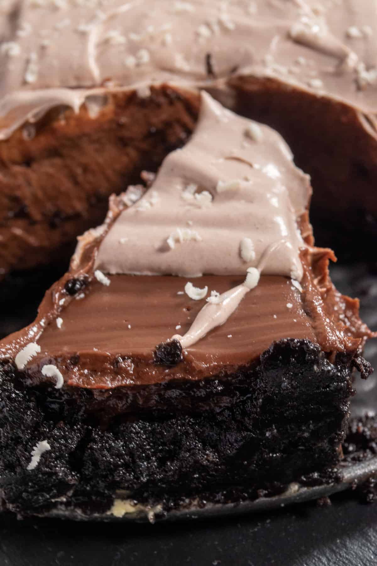 A smooth slice of vegan chocolate pudding pie on a slate chopping board. The Oreo crust looks firm and the filling looks creamy. 