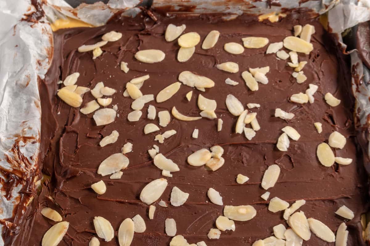 The chocolate has been poured over the custard layer and flaked almonds have been sprinkled over the top. 