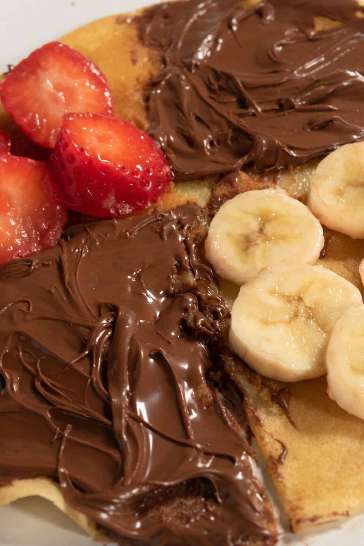 One of my unfolded vegan oat milk crepes split into four sections consisting of chocolate and fruit.