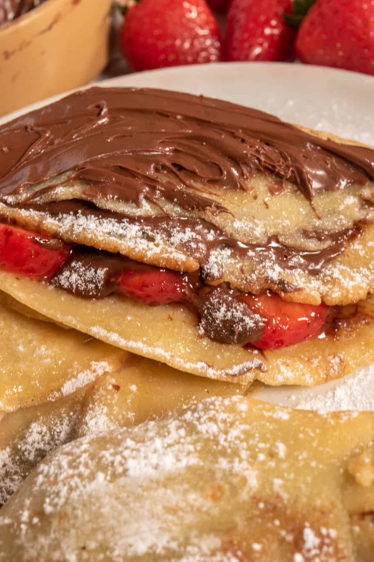 A zoomed shot of a chocolate covered crepe which is filled with fresh fruit. 
