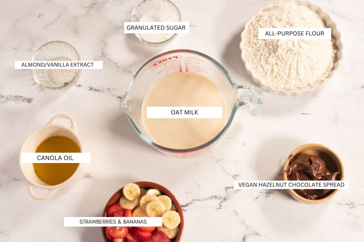 The seven recipe ingredients individually laid-out on white marble that you will need to make my vegan oat milk crepes. 