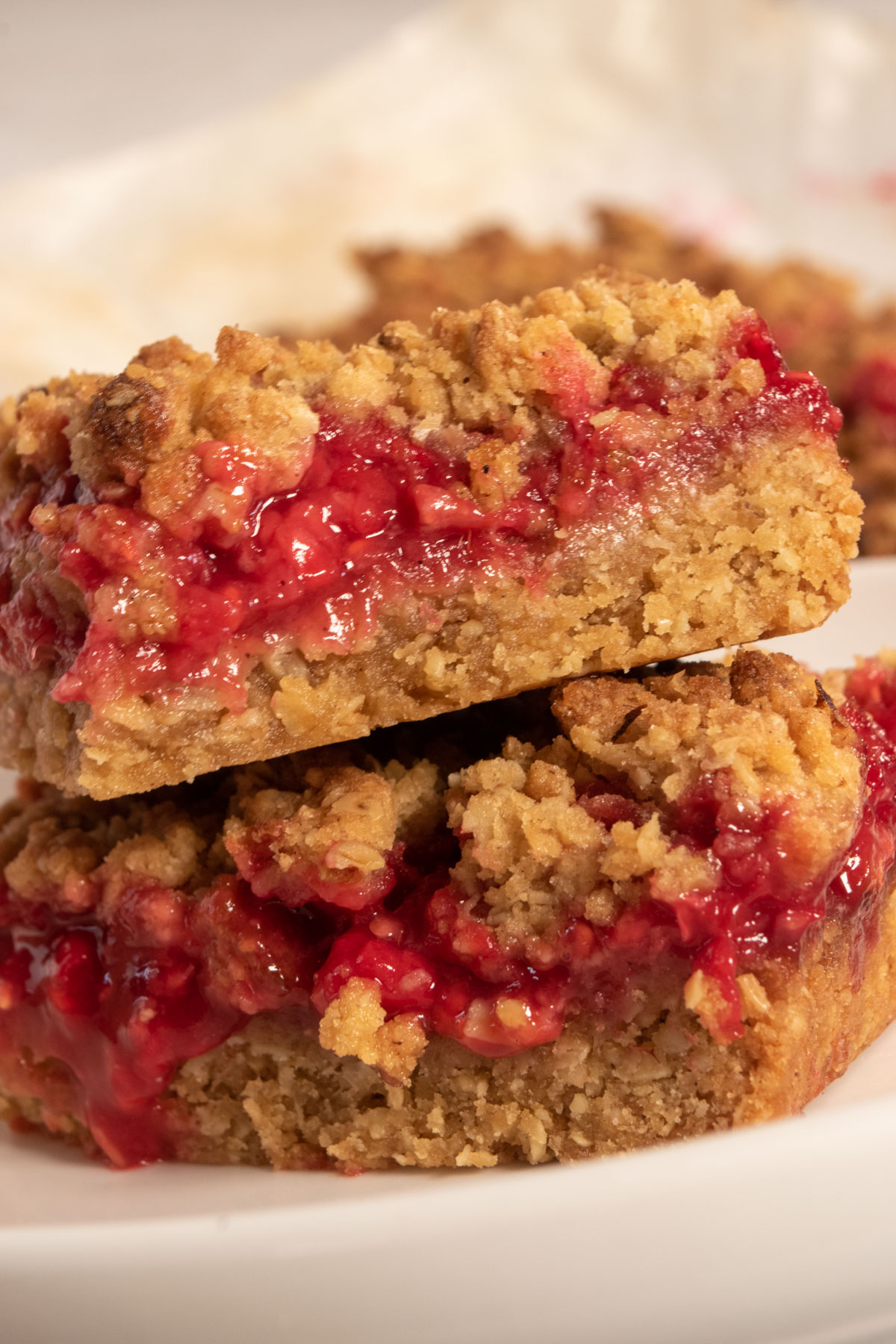 Two stacked vega raspberry bars which are golden brown and topped with lots of streusel.