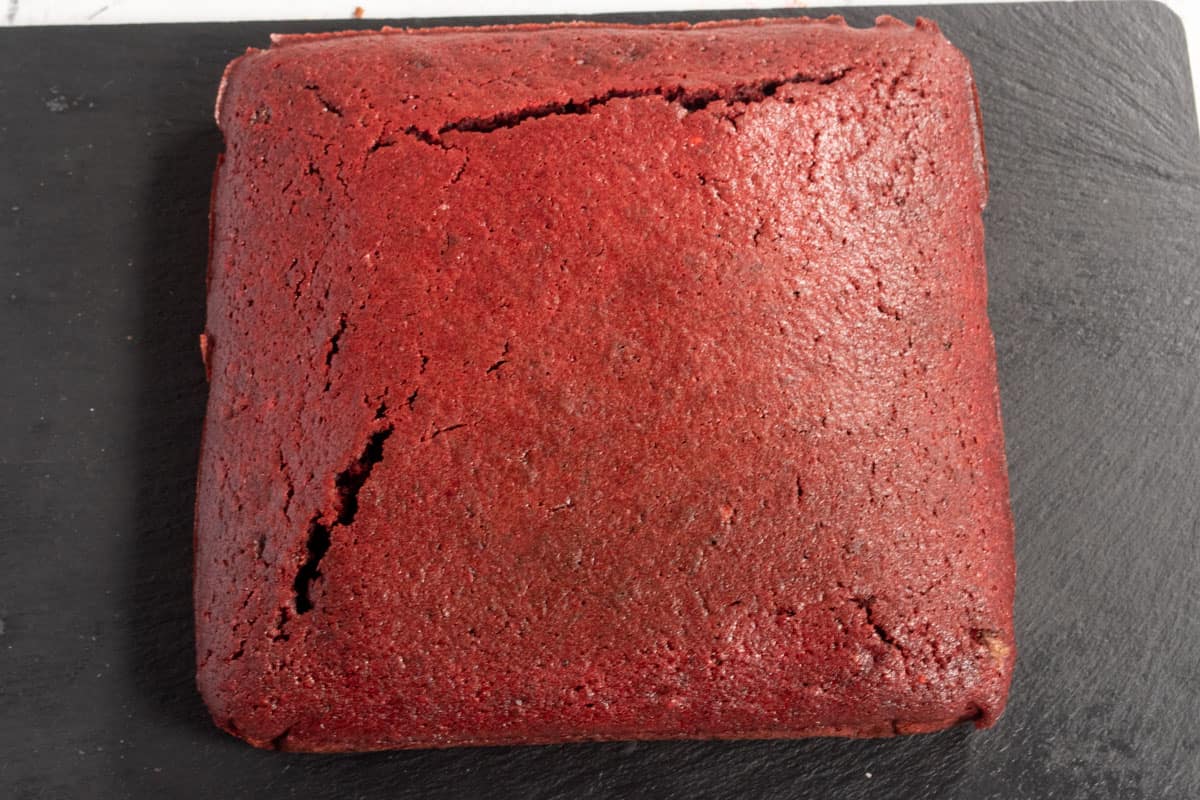 The cake has been baked and removed from the tin. It is a smooth square shape.