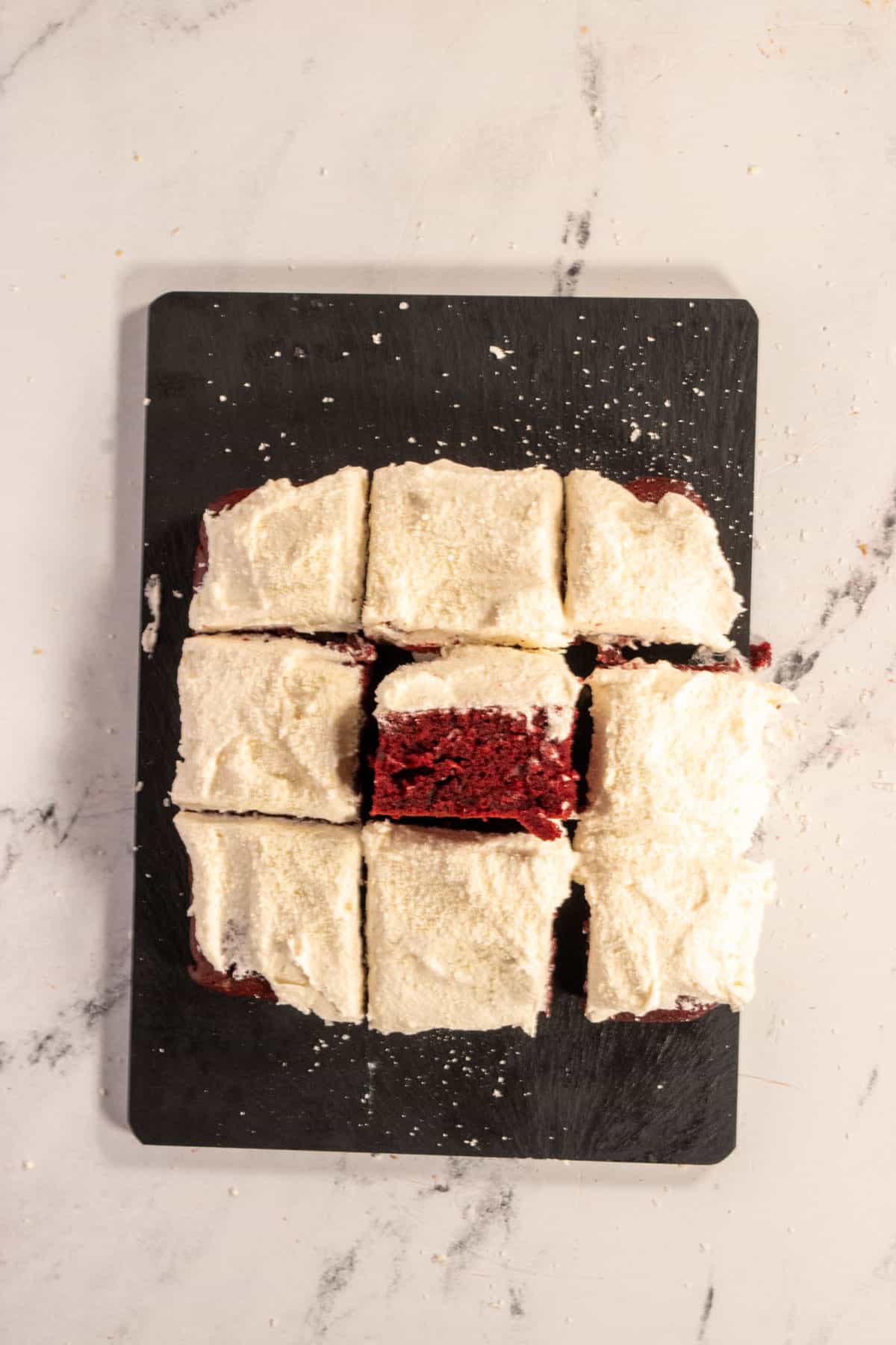 Nine slices of cake on a black serving board forming a square. The cake in the centre has been placed onto its side. 