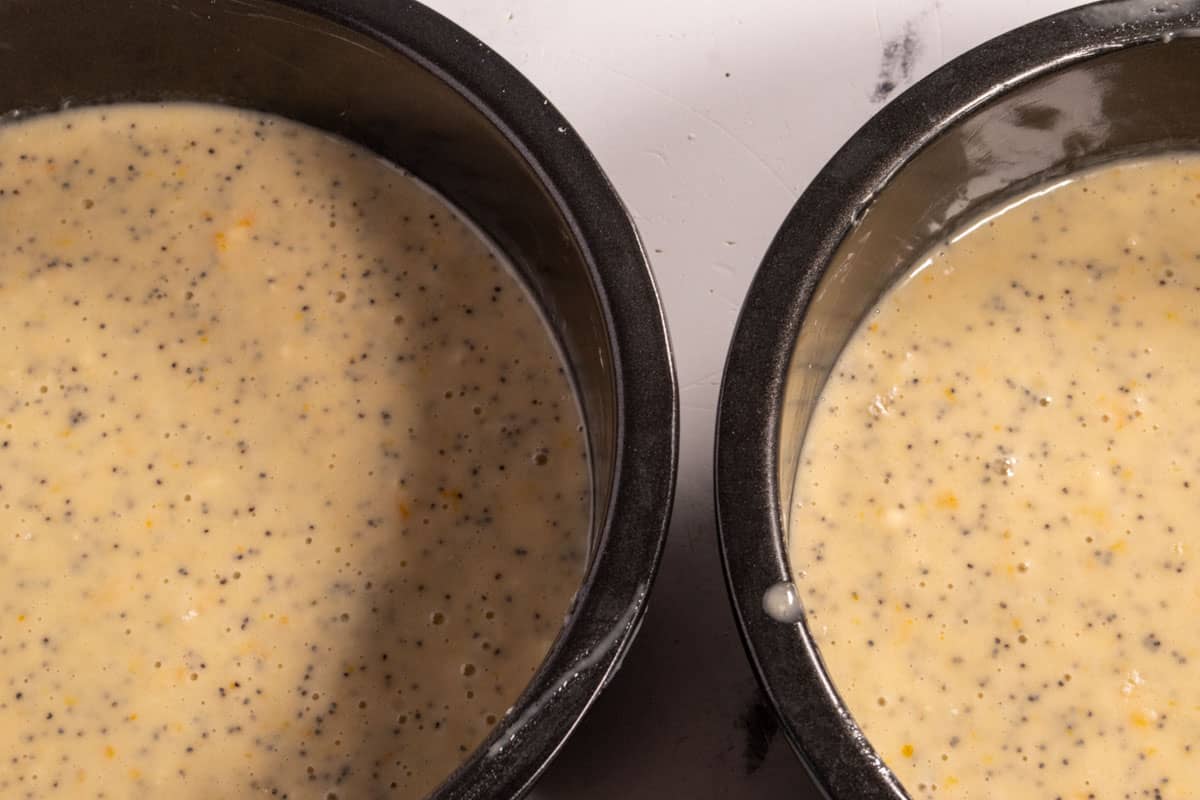 The orange cake batter has been poured into the two prepared tins. 