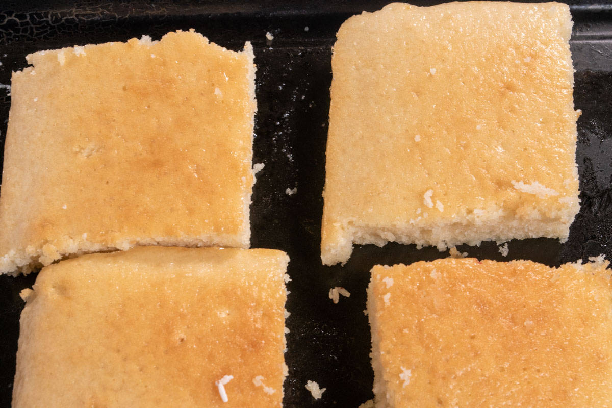 Four frozen cake squares on a black tray.