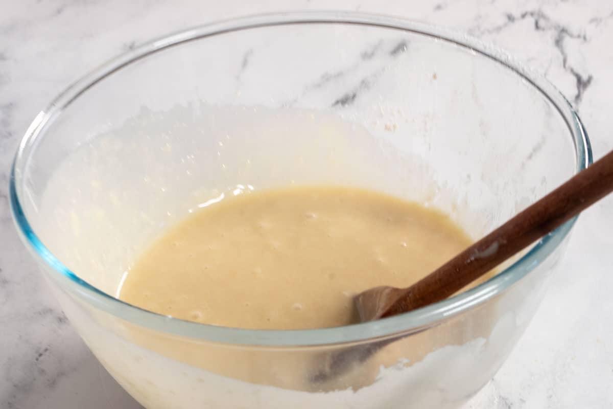 A smooth cake batter has been formed and it sits inside the bowl with a wooden spoon.