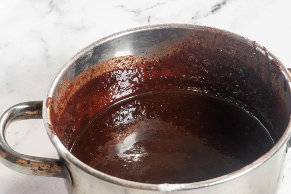 The chocolate mixture for the vegan lamingtons inside a large, metal pan.