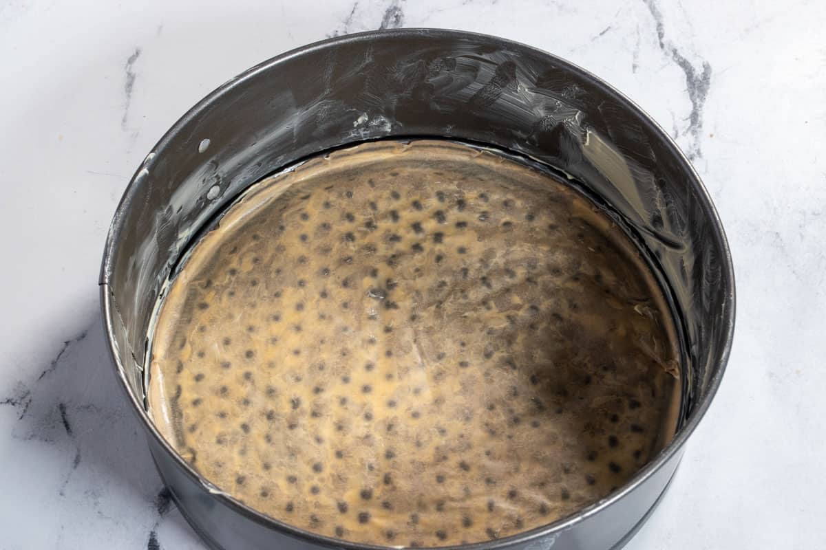 A lined, grey springform cake tin, waiting to be filled.