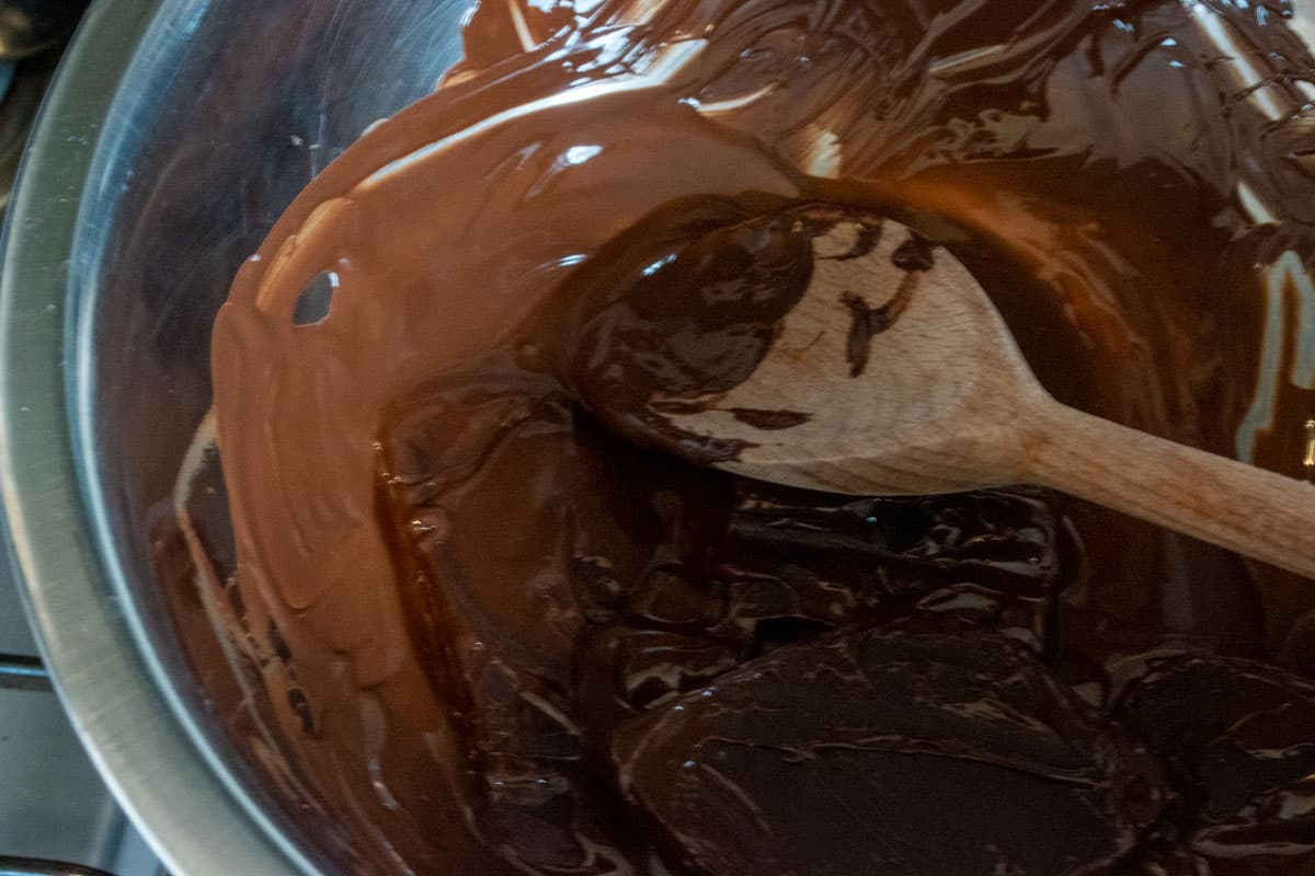 Chocolate melting inside a metal, heatproof bowl, over boiling water. 