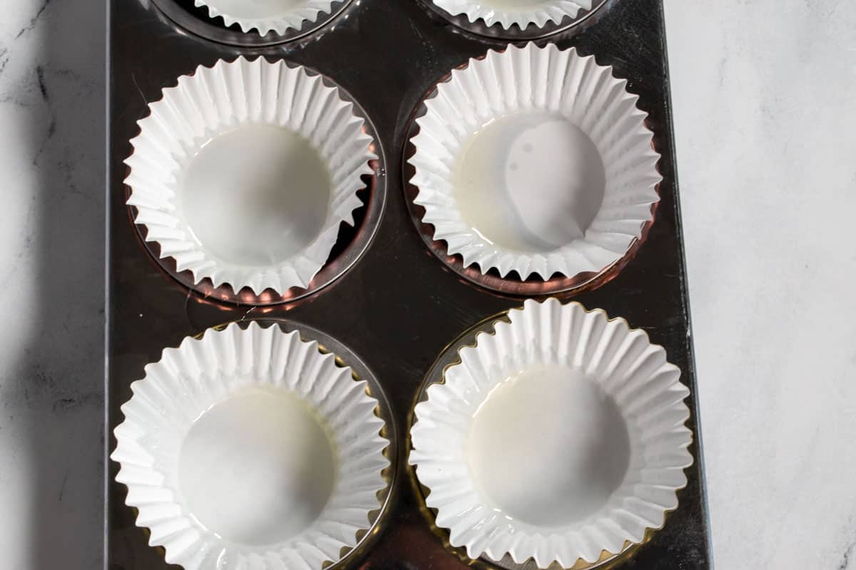 A muffin tray lined with cupcake liners. 