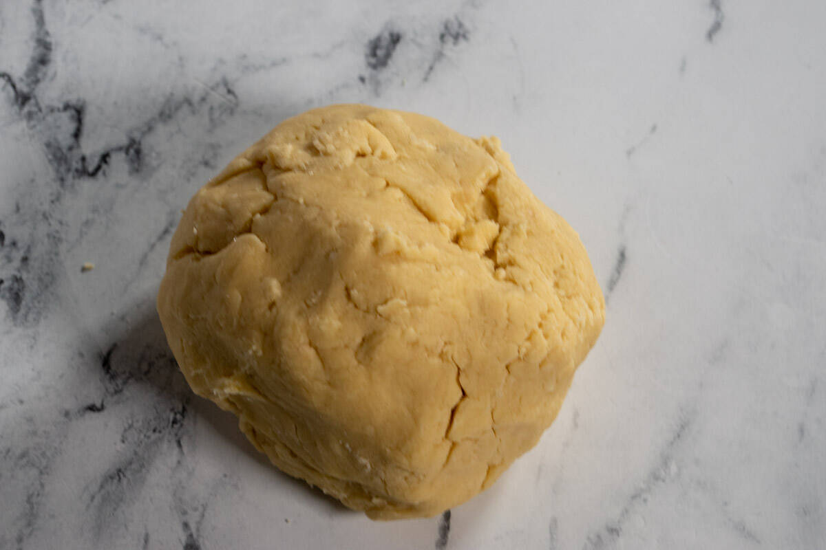 A dough ball has been created. It sits on a white, marble background.