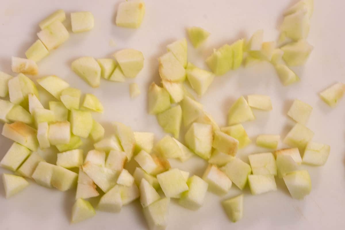 The apple chopped into small cubes on a white platter. The outer skin has also been removed. 