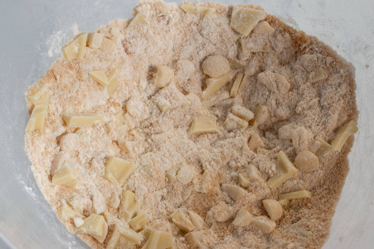 The dry ingredients including the vegan white chocolate and the macadamia nuts are combined in a large bowl. 