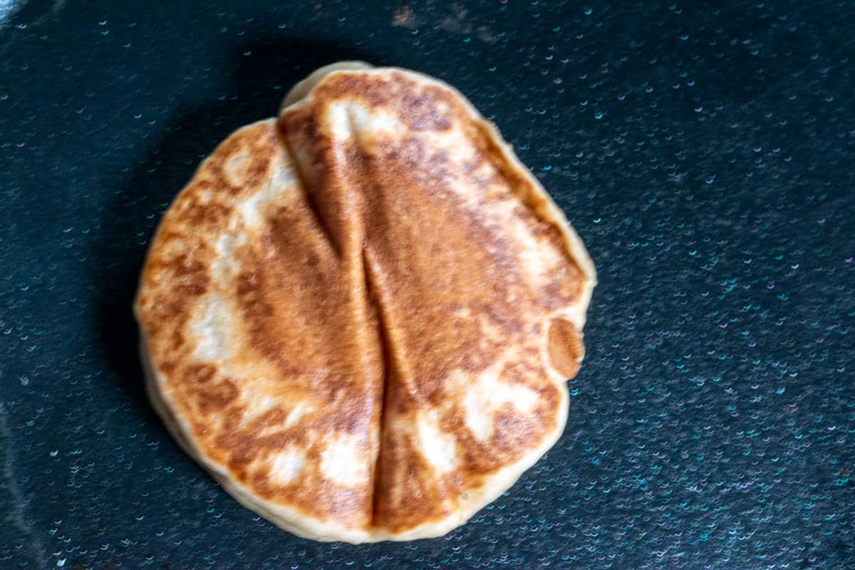 The pancake has been cooked on one side. The golden brown side now showing. 