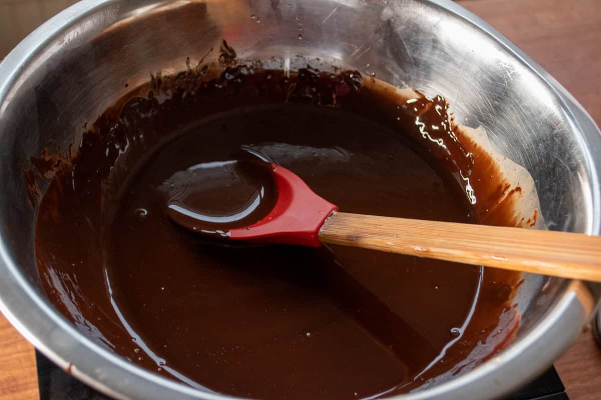 Chocolate melted inside a large, metal mixing bowl. 